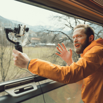 Man in yellow jacket filming himself while on a train